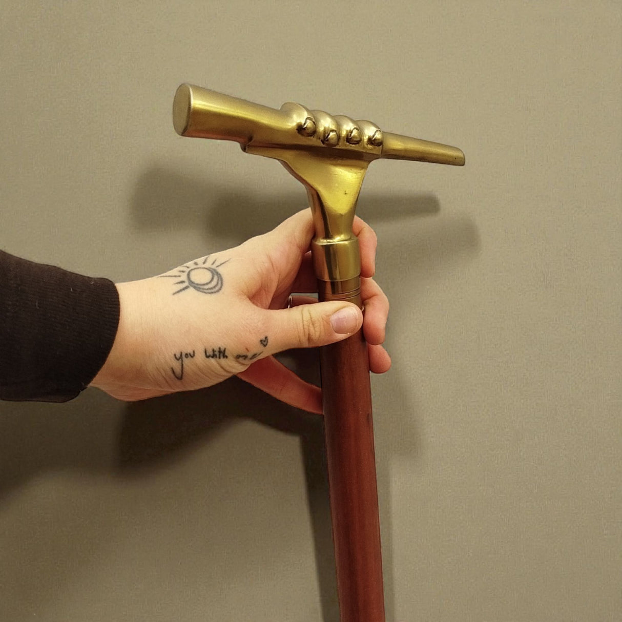 Hand mit Fernrohr Spazierstock aus Holz mit goldenem Griff aus Metall