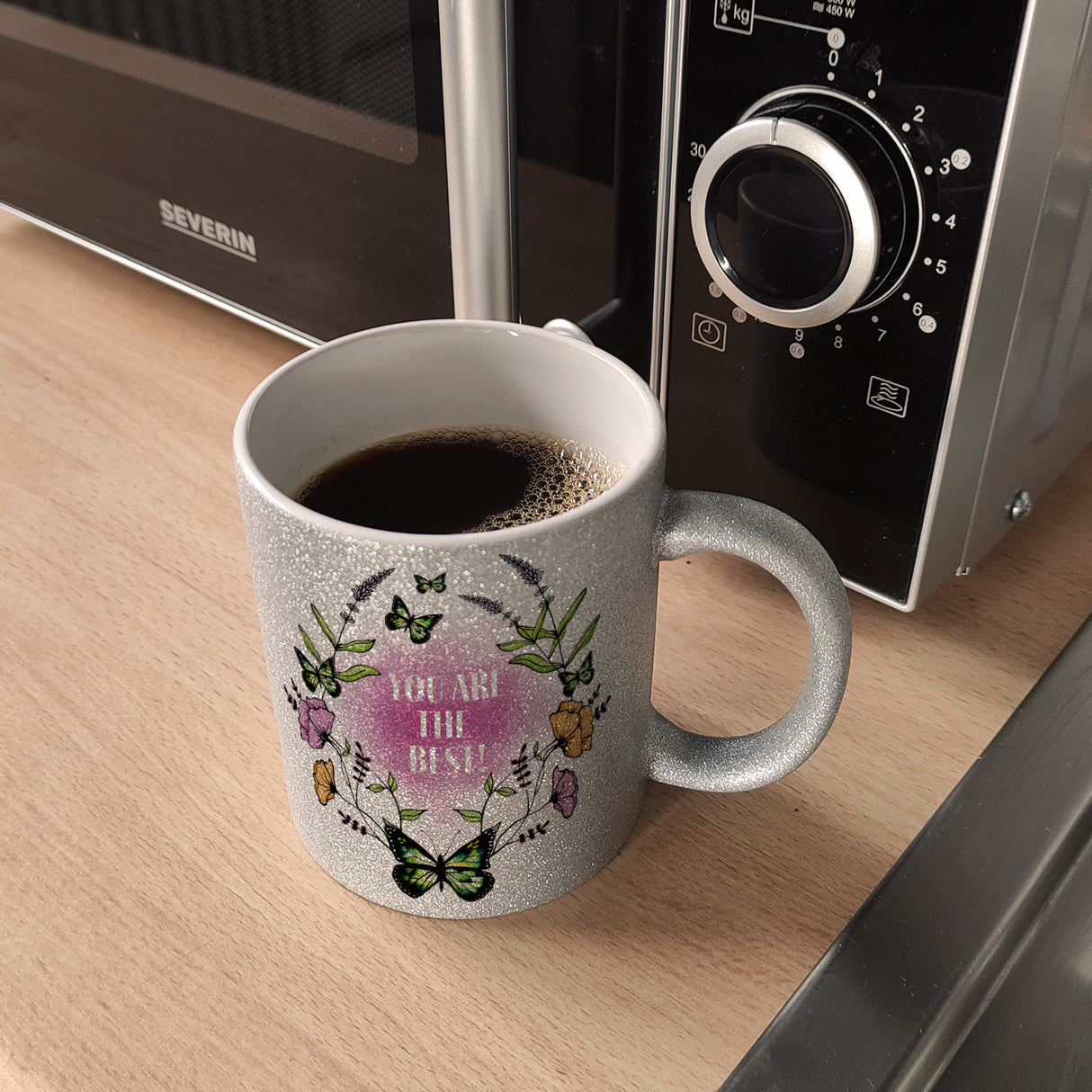 Kaffeebecher mit motivierenden Worten und Blumenrahmen mit Schmetterlingen
