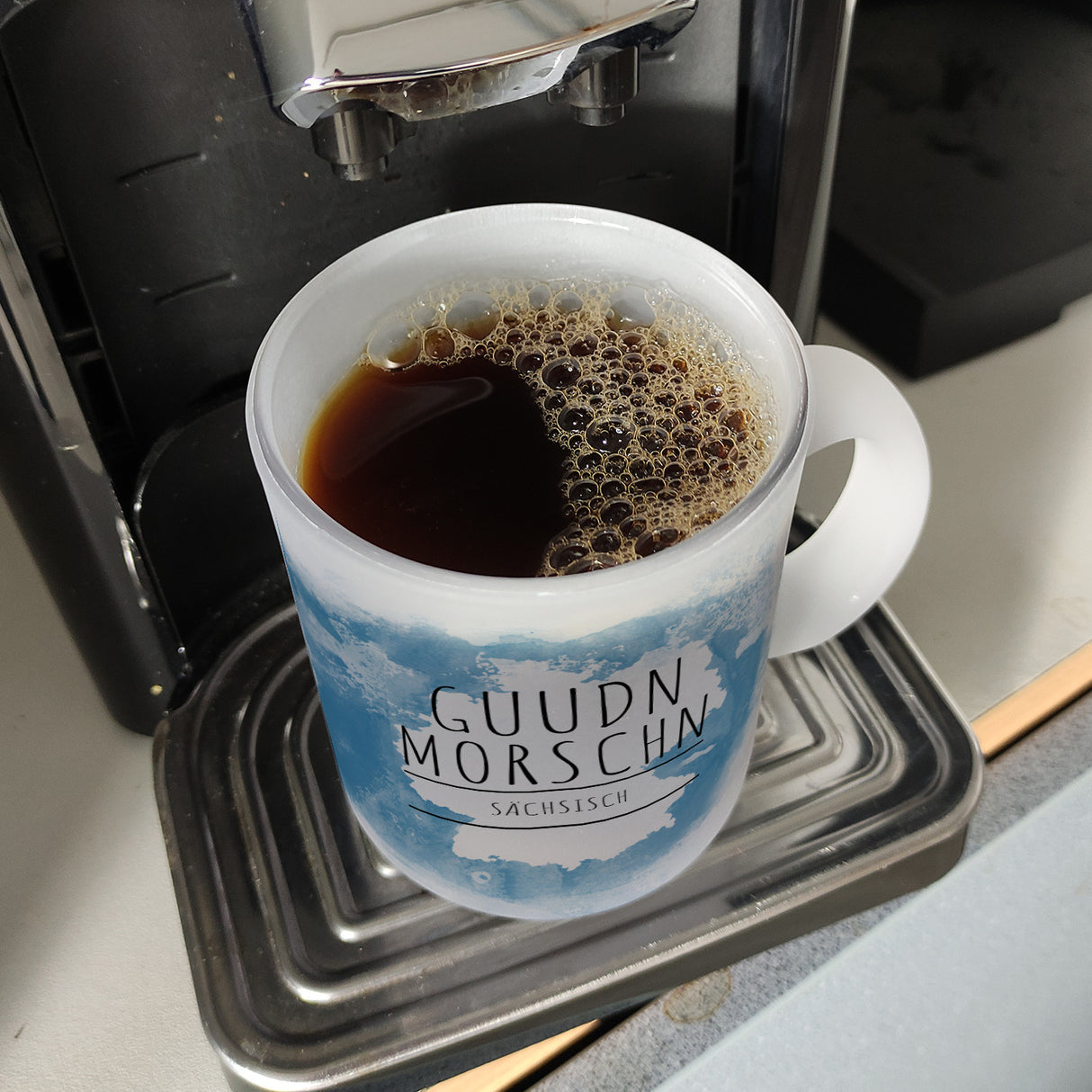 Hallo auf Sächsisch Guudn Morschen lustiger Kaffeebecher mit blauem Hintergrund