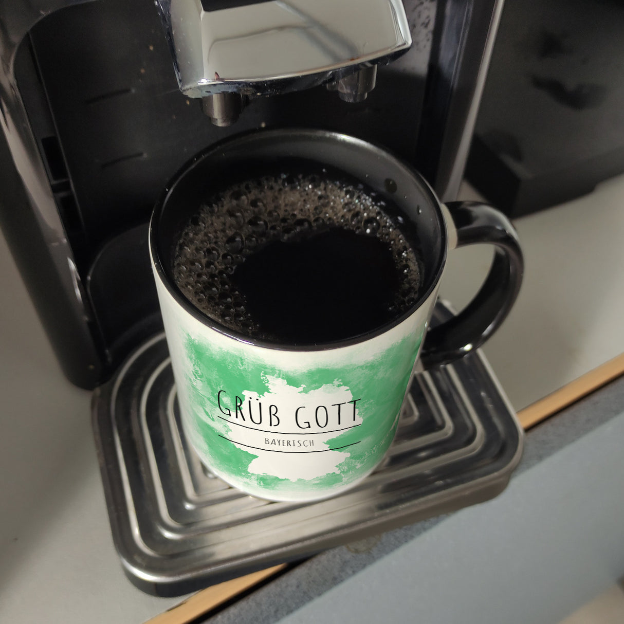 Hallo auf Bayerisch Grüß Gott lustiger Kaffeebecher mit grünem Hintergrund