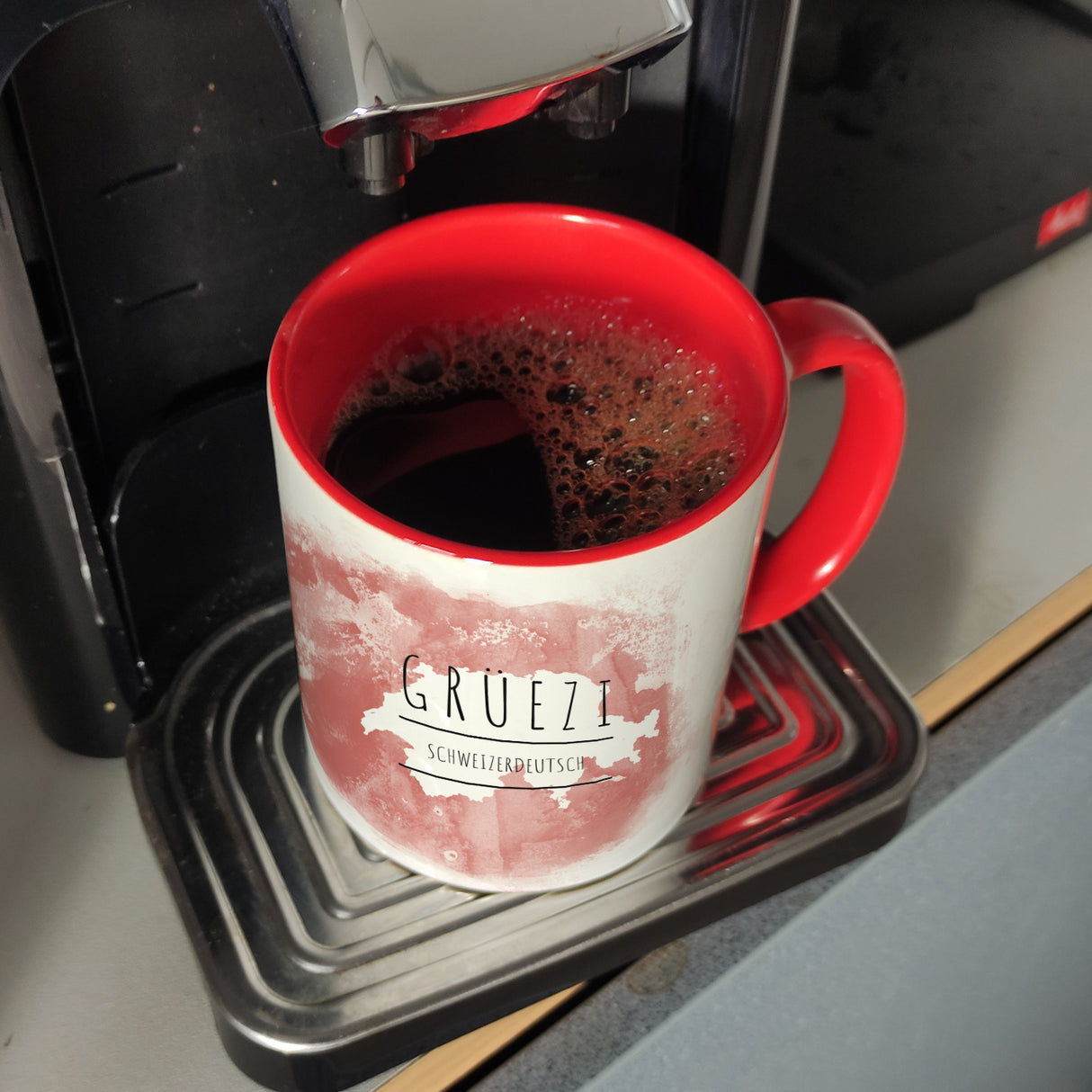 Hallo auf Schweizerdeutsch Grüezi lustiger Kaffeebecher mit rotem Hintergrund