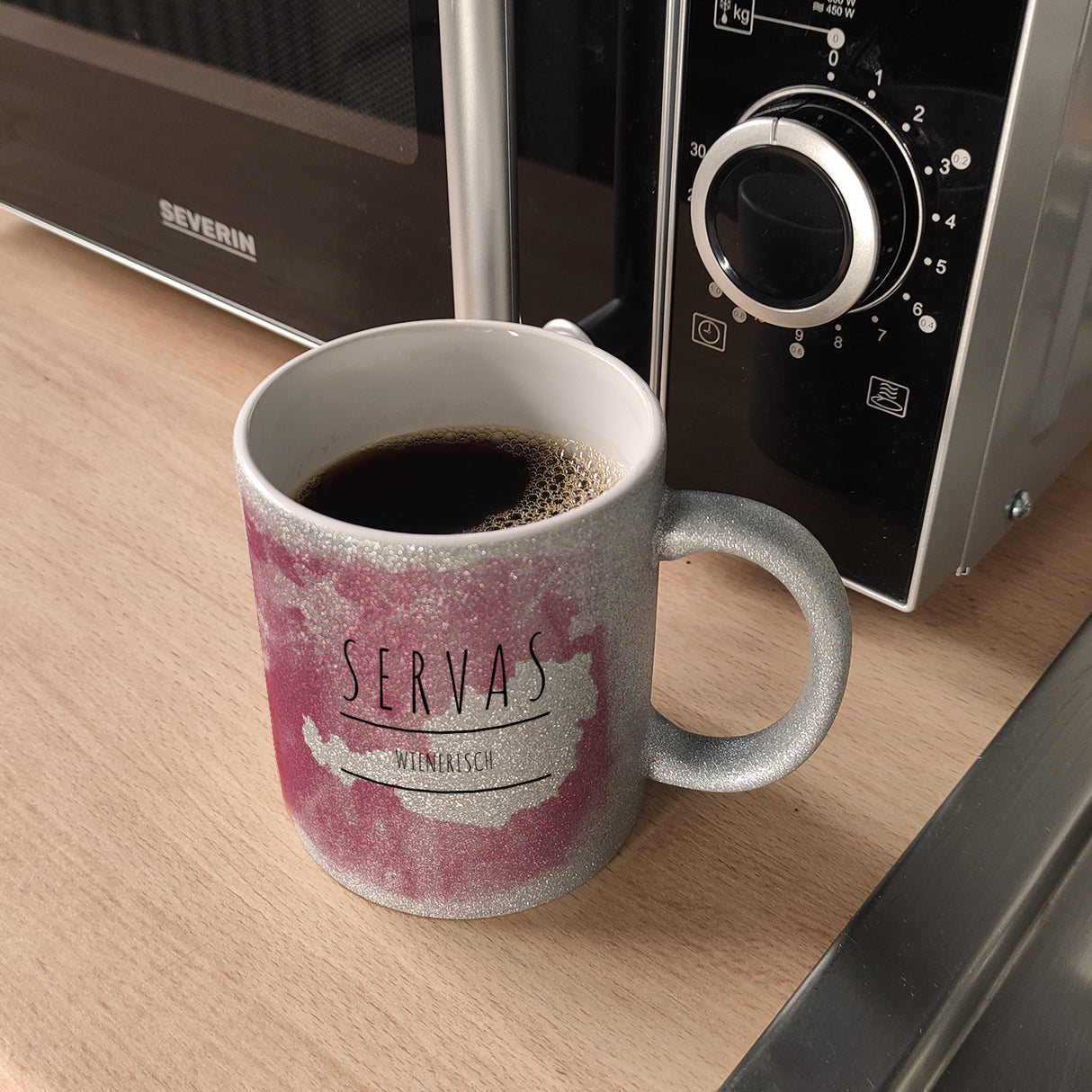 Hallo auf Wienerisch Servas lustiger Kaffeebecher mit rosaem Hintergrund