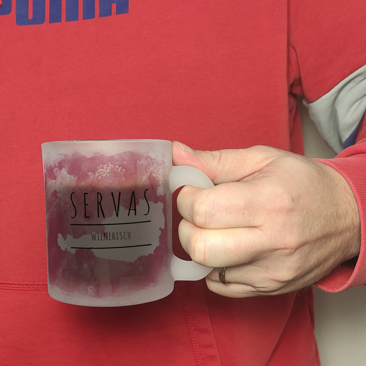Hallo auf Wienerisch Servas lustiger Kaffeebecher mit rosaem Hintergrund
