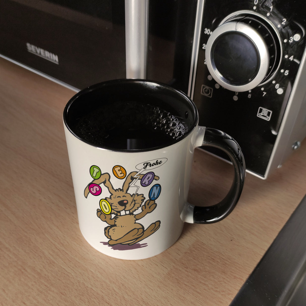 Frohe Ostern! Osterhase jongliert mit Ostereiern Kaffeebecher in {weiß}