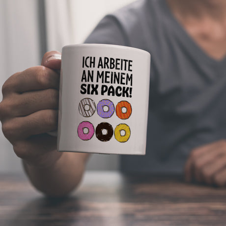 Ich arbeite an meinem Six Pack Kaffeebecher mit bunten Donuts