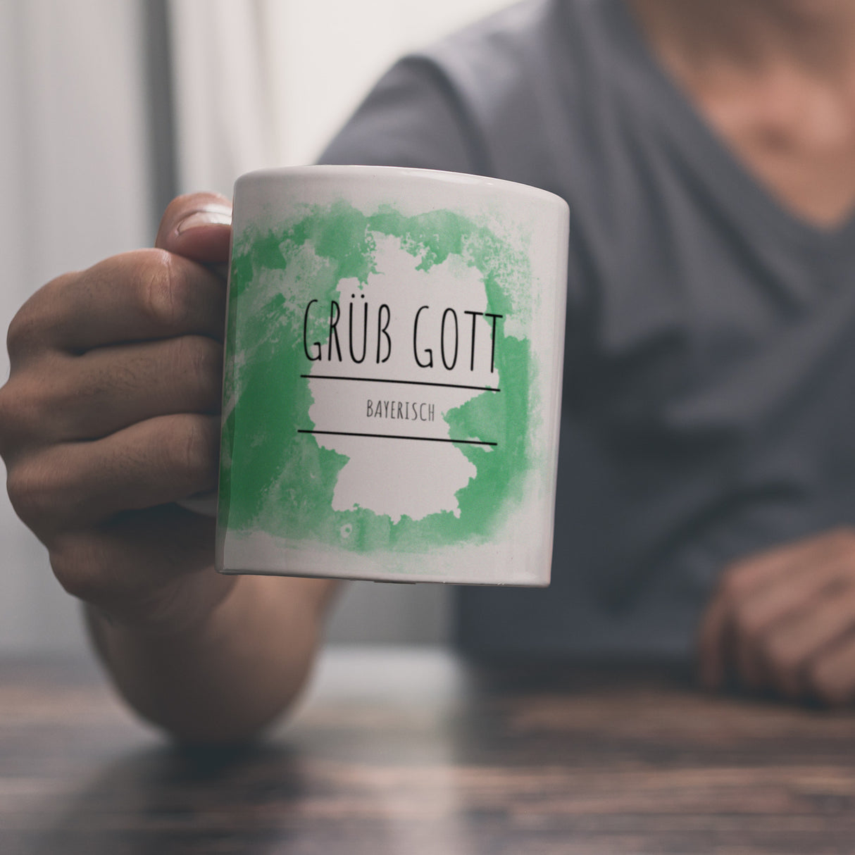 Hallo auf Bayerisch Grüß Gott lustiger Kaffeebecher mit grünem Hintergrund
