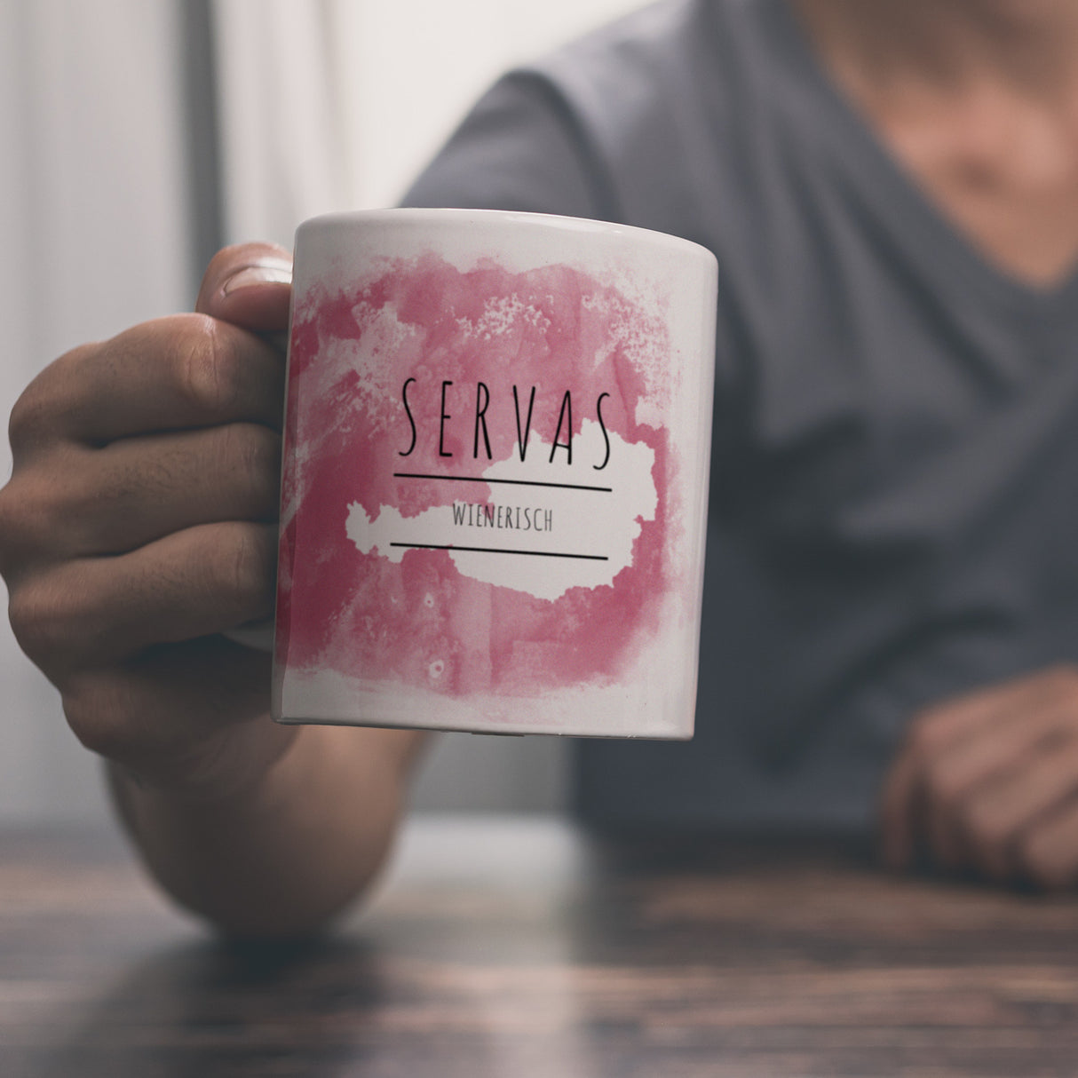 Hallo auf Wienerisch Servas lustiger Kaffeebecher mit rosaem Hintergrund