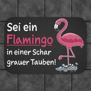 Sei ein Flamingo in einer Schar grauer Tauben Badematte